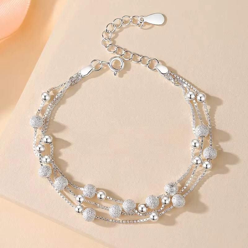 Bracelet Argenté Double Chaine à Perles sur fond beige