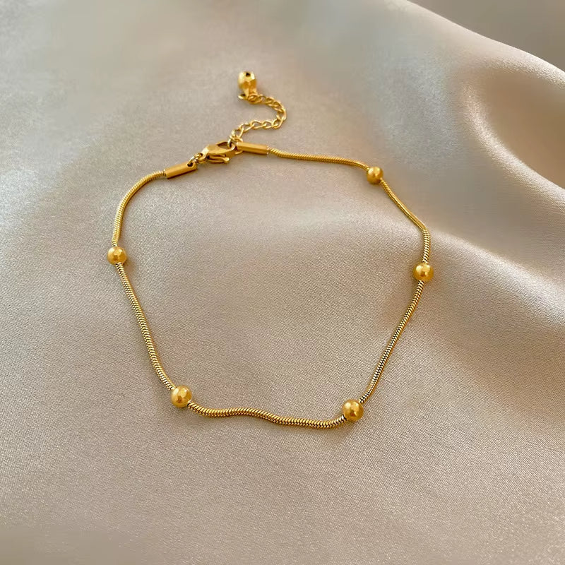 Bracelet Cheville Femme Chic en Acier Inoxydable sur fond beige