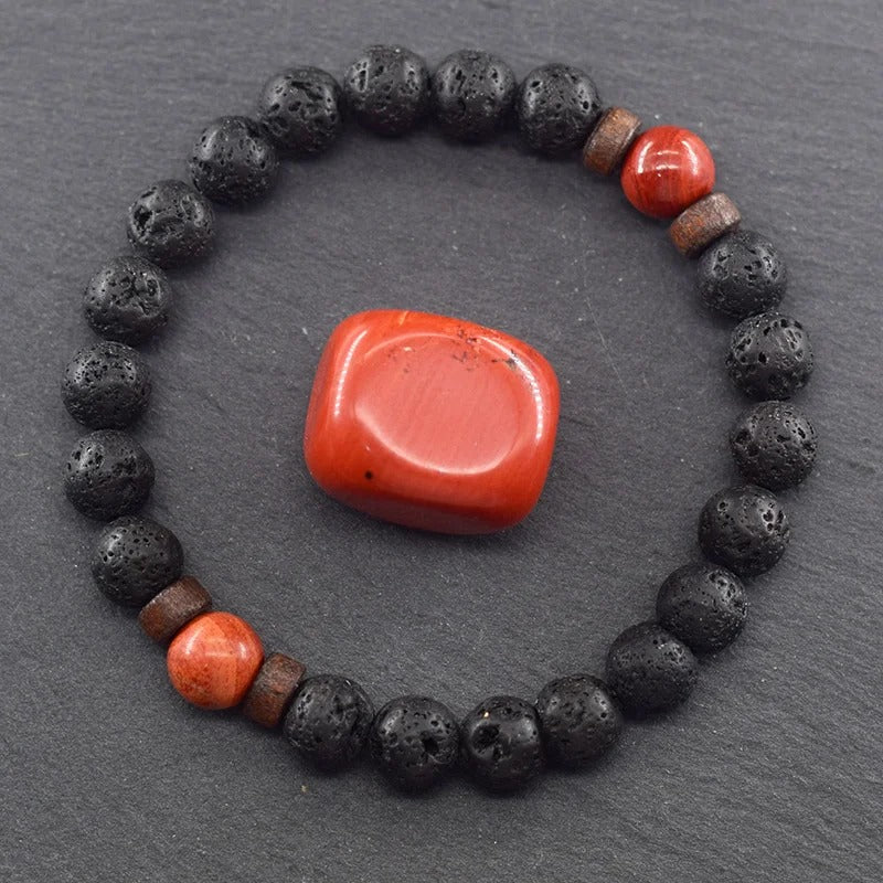Bracelet Jaspe Rouge et Perles de Lave sur fond gris foncé avec une pierre de jaspe rouge au centre