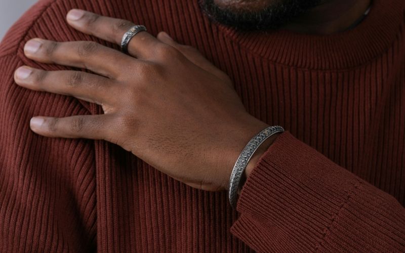 main d'homme sur laquelle on voit une bague, et un bracelet assorti au poignet.