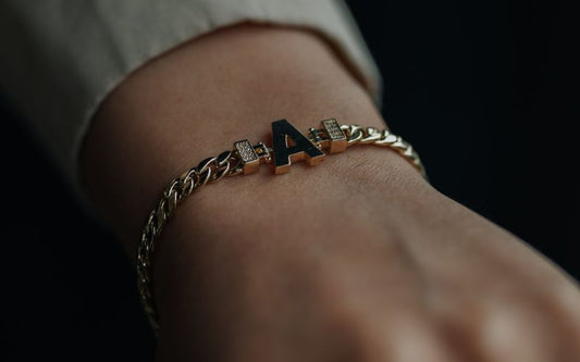 Poignet homme portant un superbe bracelet homme doré avec la lettre A.