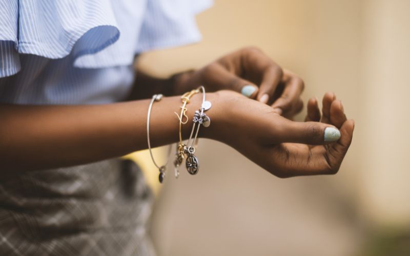Bras de femme avec plusieurs bracelets fin dont un avec initiale.