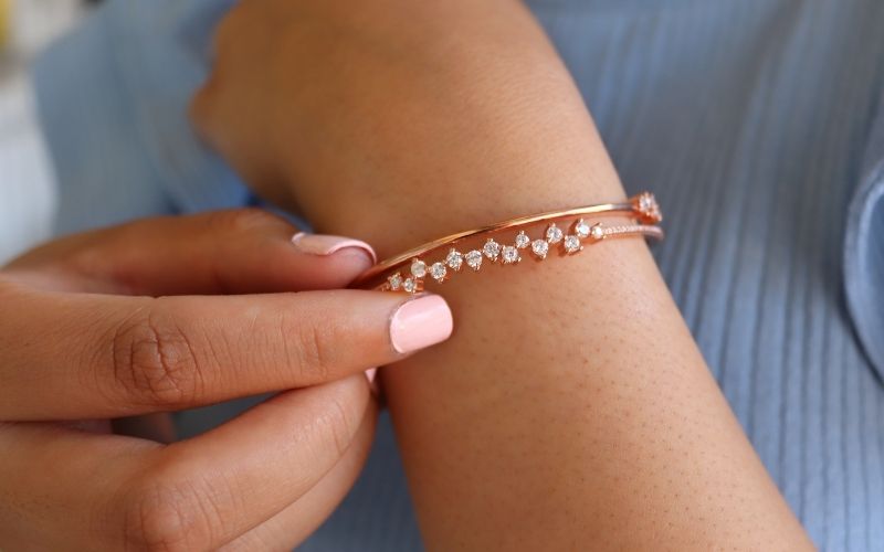 Bras femme portant un bracelet aspect jonc, avec des pierres zircon.