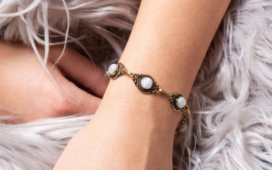 poignet de femme qui porte un bracelet, avec des pierre blanches.