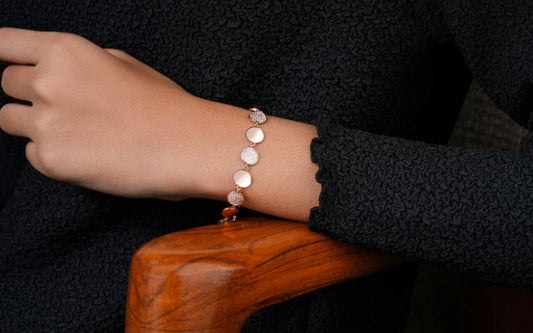 Bras de femme, avec bracelet délicat avec des petits cercles comme des pétales de fleur nacré et strass.