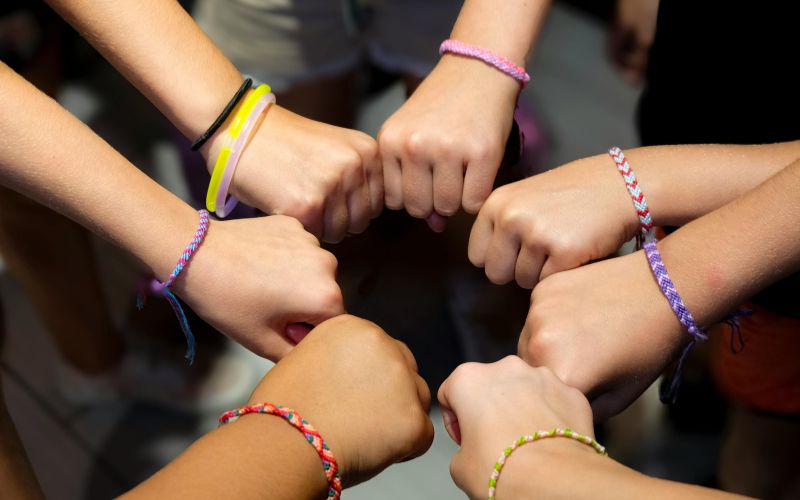 Plusieurs bras d'enfant qui se réunissent au centre avec chacun des bracelet tennis ou indien