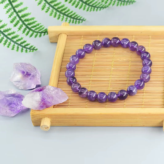 Bracelet Améthyste à Perles Rondes sur un plateau en bois