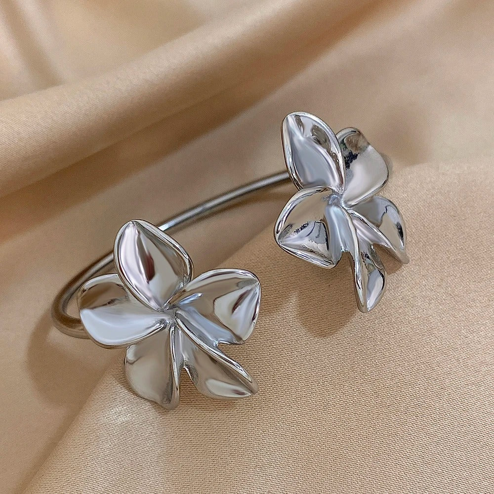 Bracelet De Bras Femme Double Fleur argenté présenté sur un tissu beige et satiné