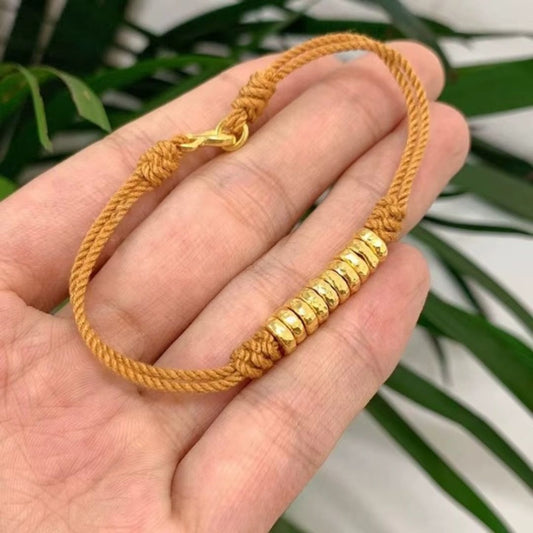 Bracelet Jaune Tressé en Argent dans une main sur fond de plantes